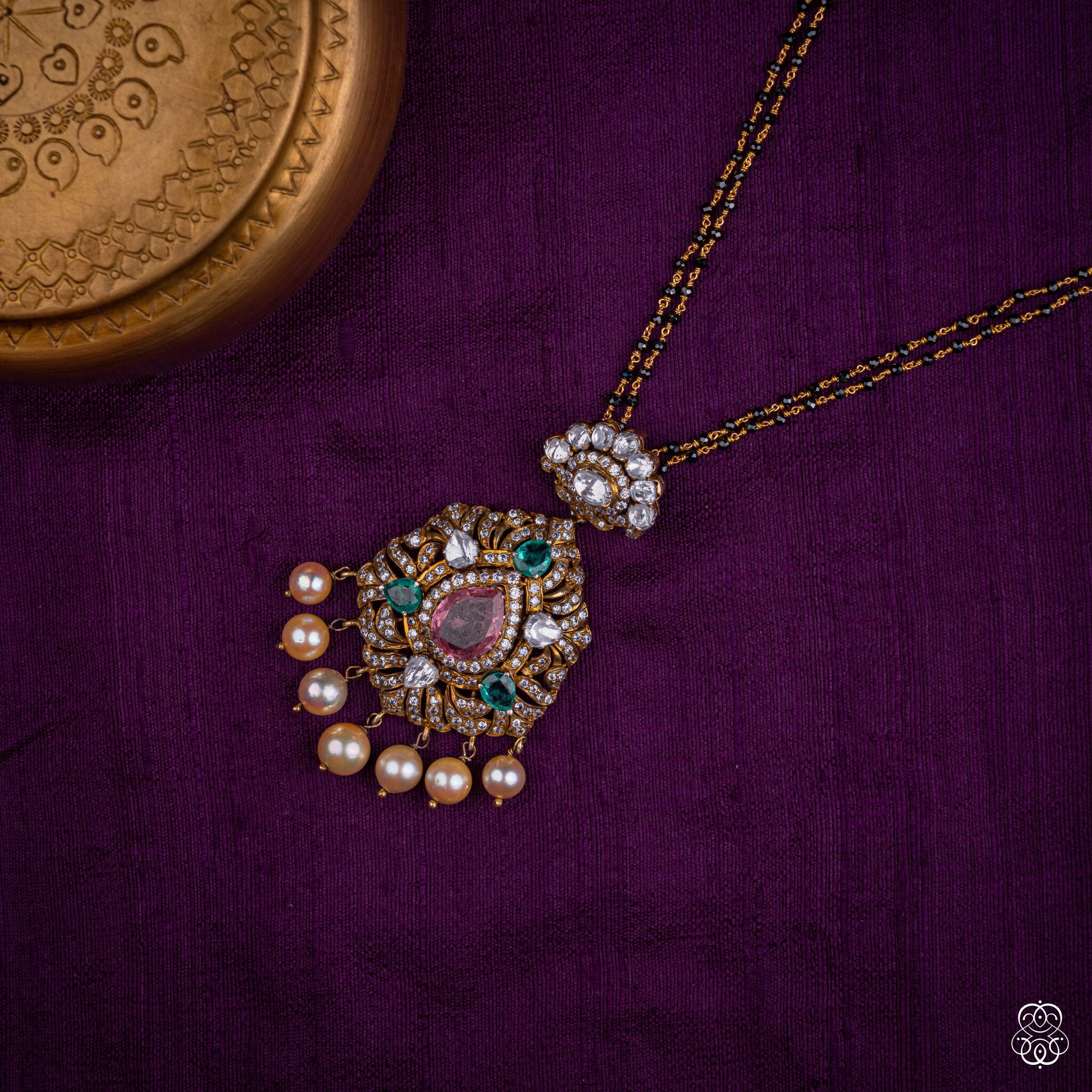 Padmaraga tourmaline and emerald pendant styled on a black bead chain