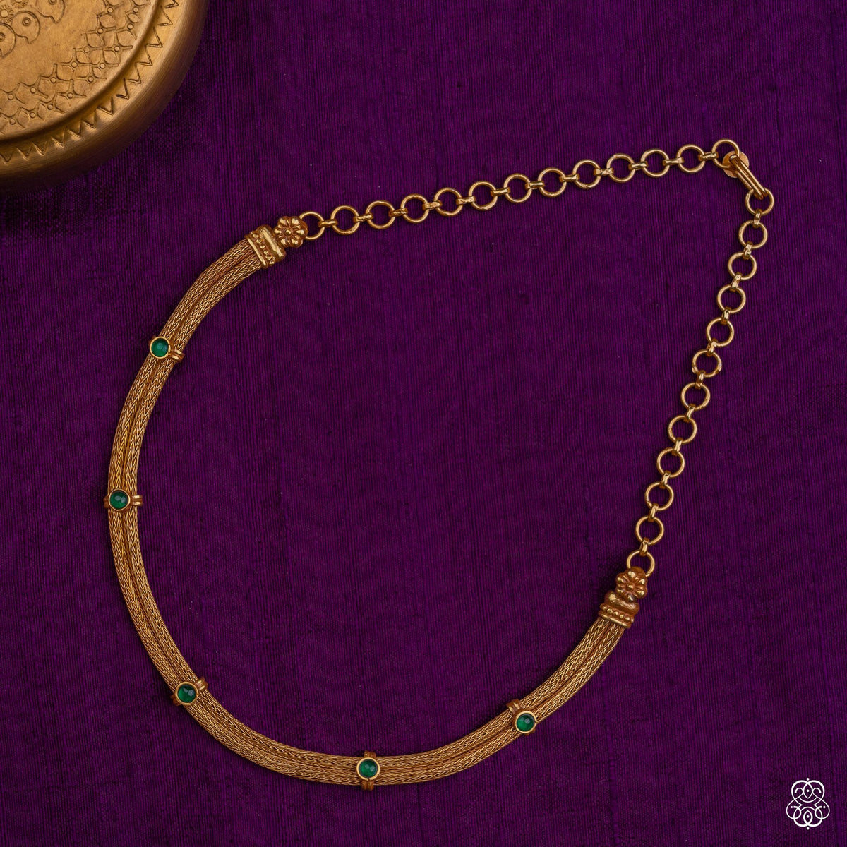 Close view of the emerald settings on the Venimala braided gold necklace
