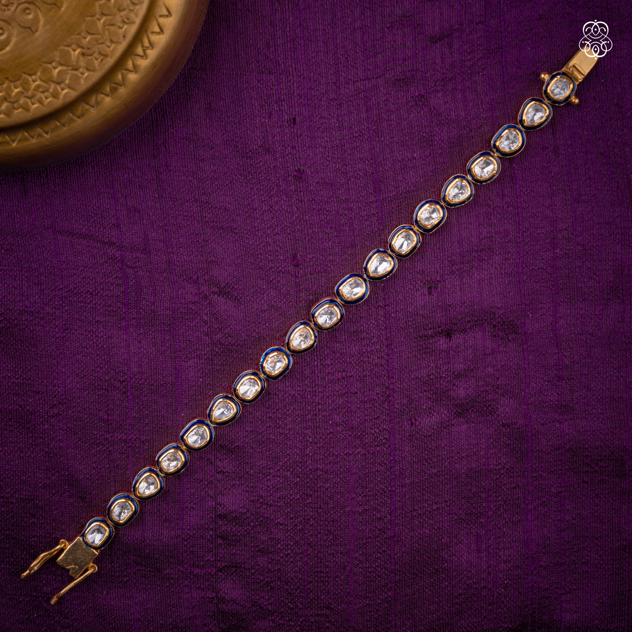 A gold-plated traditional Indian bracelet adorned with round blue and white enamel inlays.