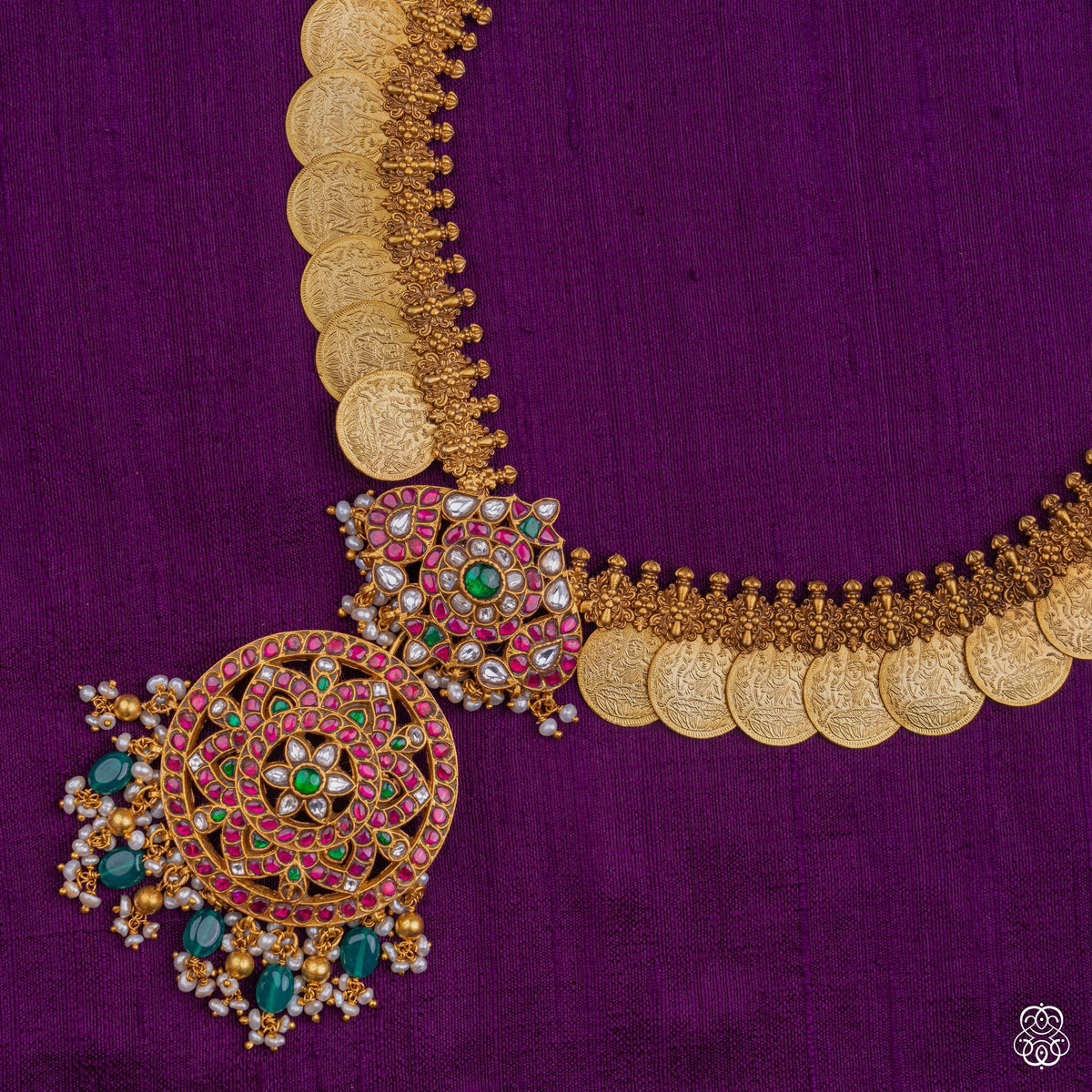 Close view of the kundan, ruby and emerald pendant on the Swarna Lakshmi Kasumala coin necklace